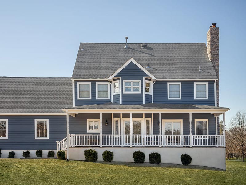 blue house with white porch railing and columns